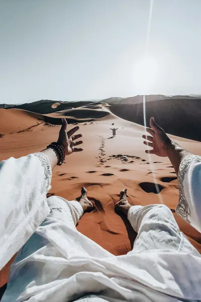 A traveller resting barefoot on a sand dune in the desert